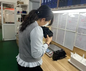 Woman inspecting electrical component in workshop.